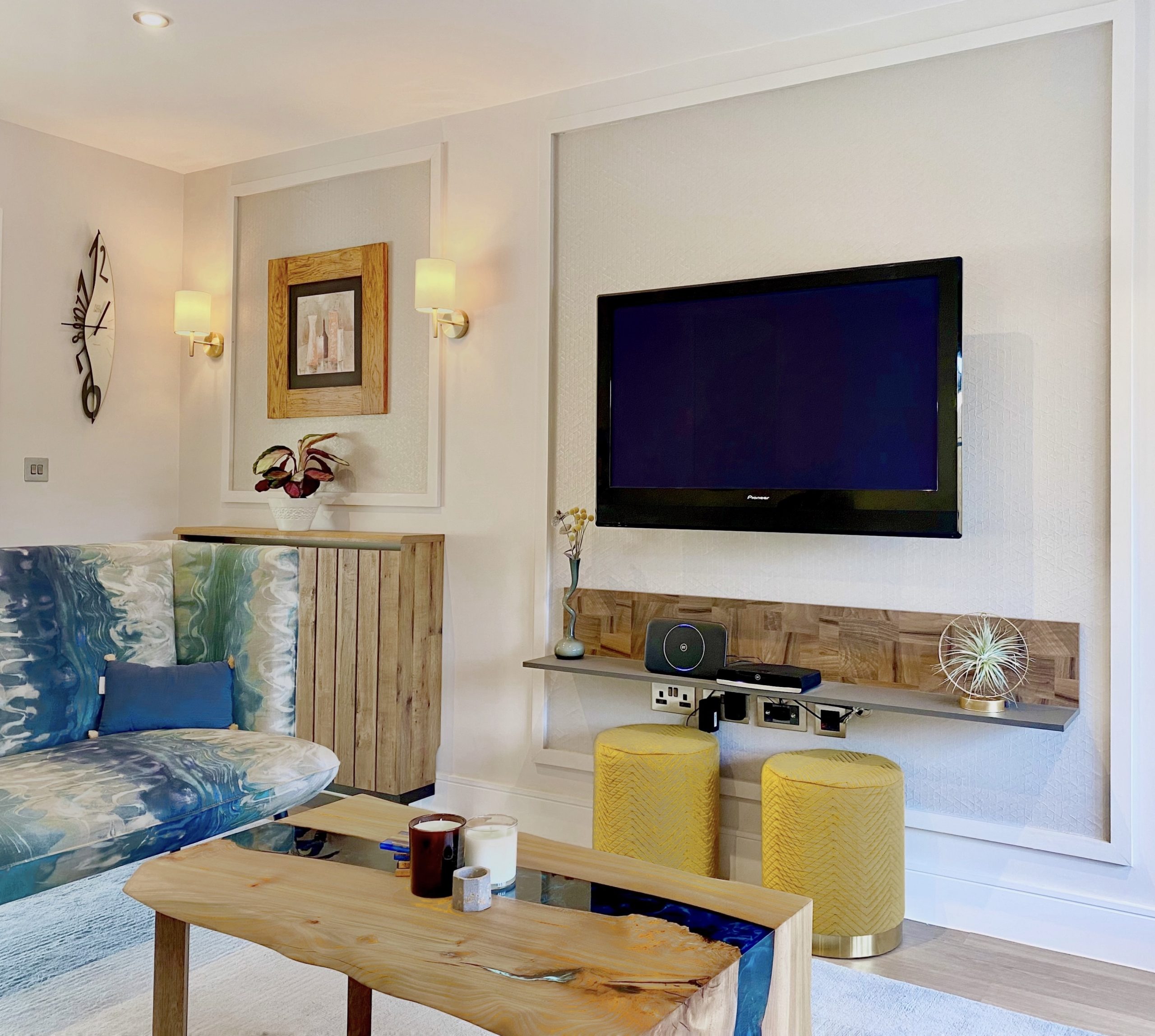 Media wall with timber panelling, framed art and blue patterned seating