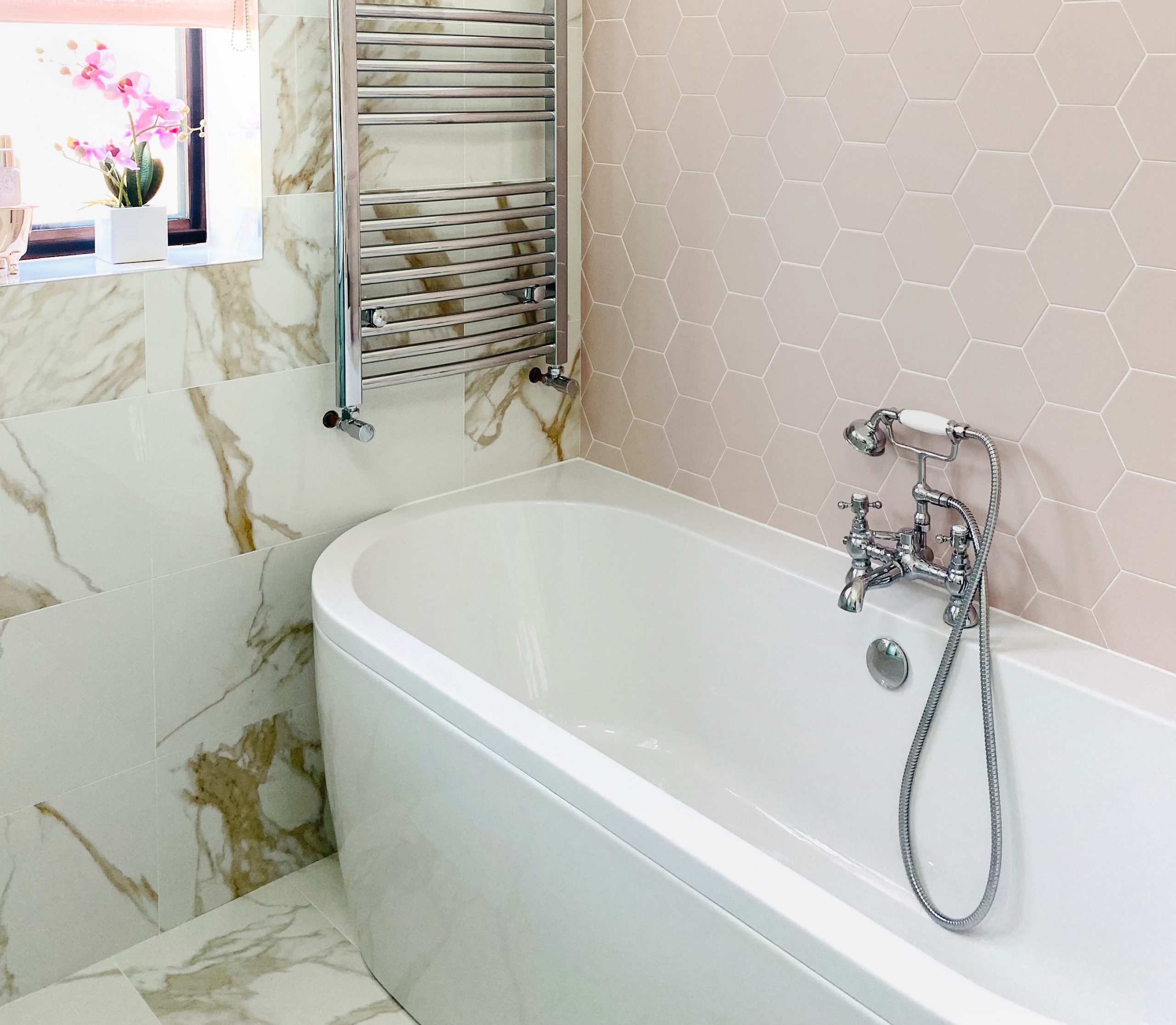 En suite bath with chrome mixer tap, pink hexagon tiles and marble effect tiling